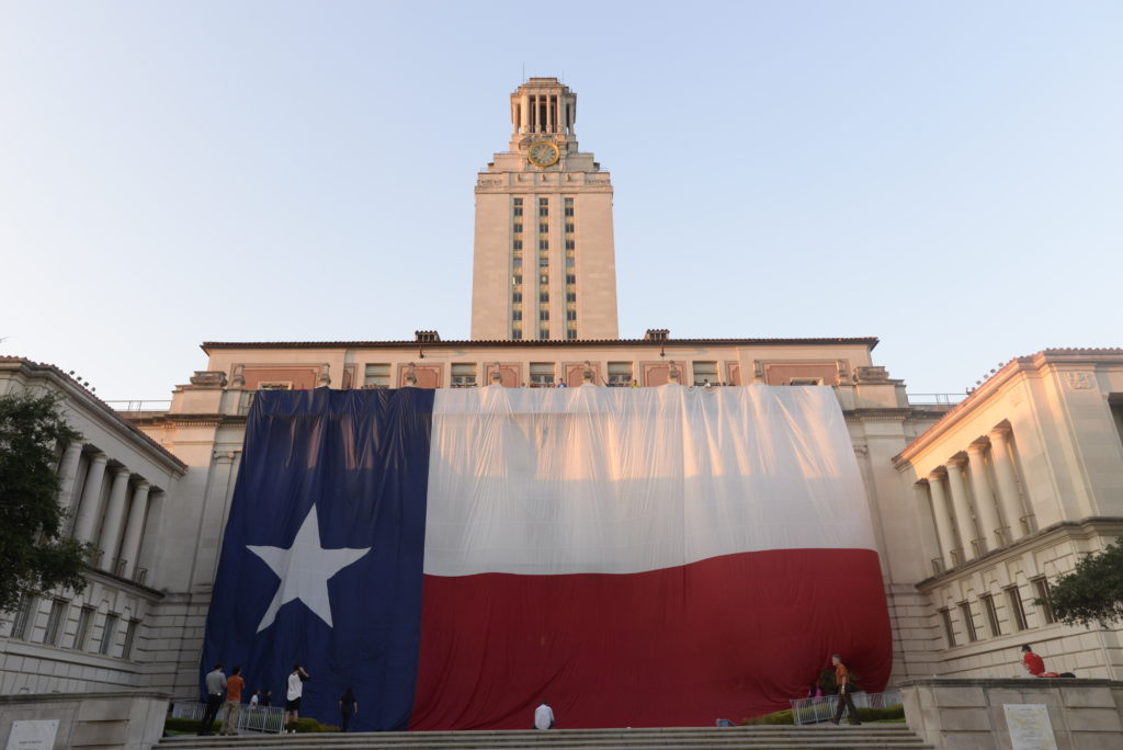 The Texas flag hangs from the Main Building in front of the UT Tower 
