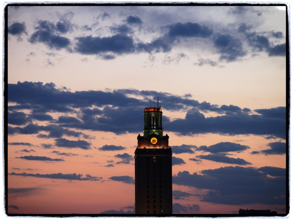 UT Tower pictured dark against a dusk sky with cloulds
