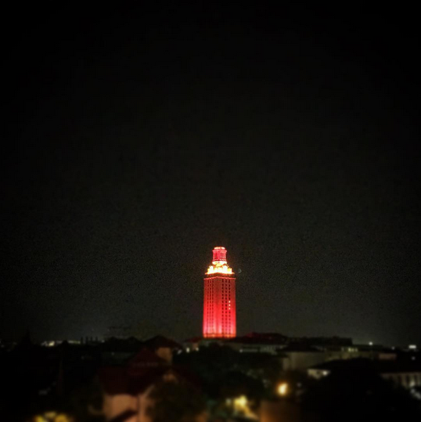 UT Tower glows bright orange in the distance against a dark night sky