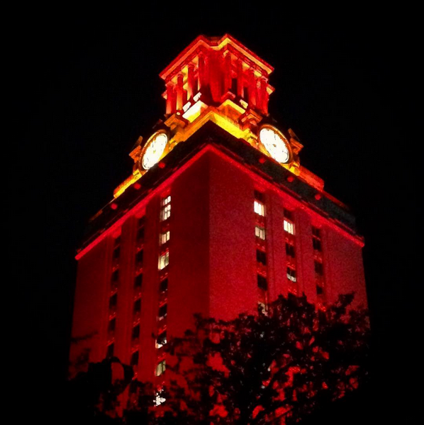 Top of the UT Tower shown glowing orange against a black background