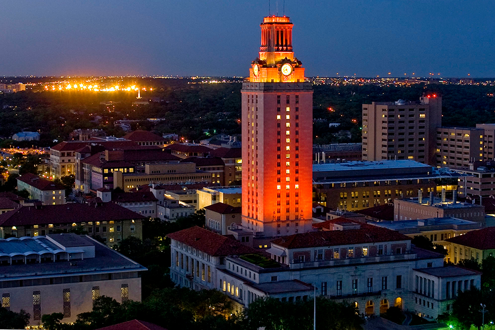 UT Tower glowing orange with the number one showing among the other buildings on campus at dusk