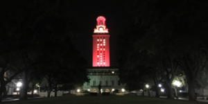 The UT Tower shines with burnt orange lights and the number “21” displayed on its sides.