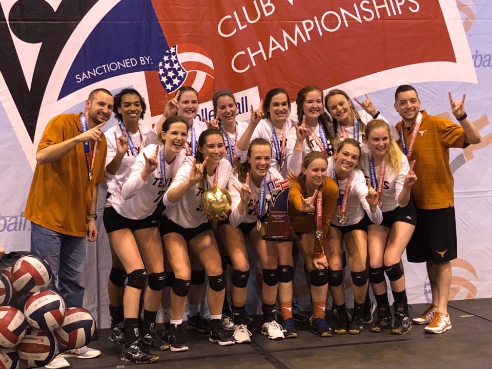 Volleyball students pose with a trophy and golden volleyball in front of a championship banner