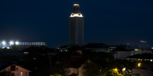 With darkened lights, the UT Tower stands above the campus at night.
