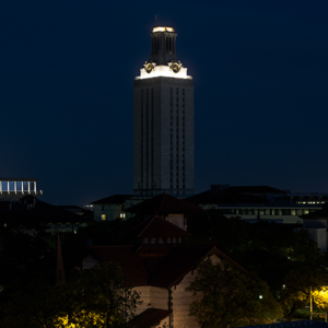 With darkened lights, the UT Tower stands above the campus at night.