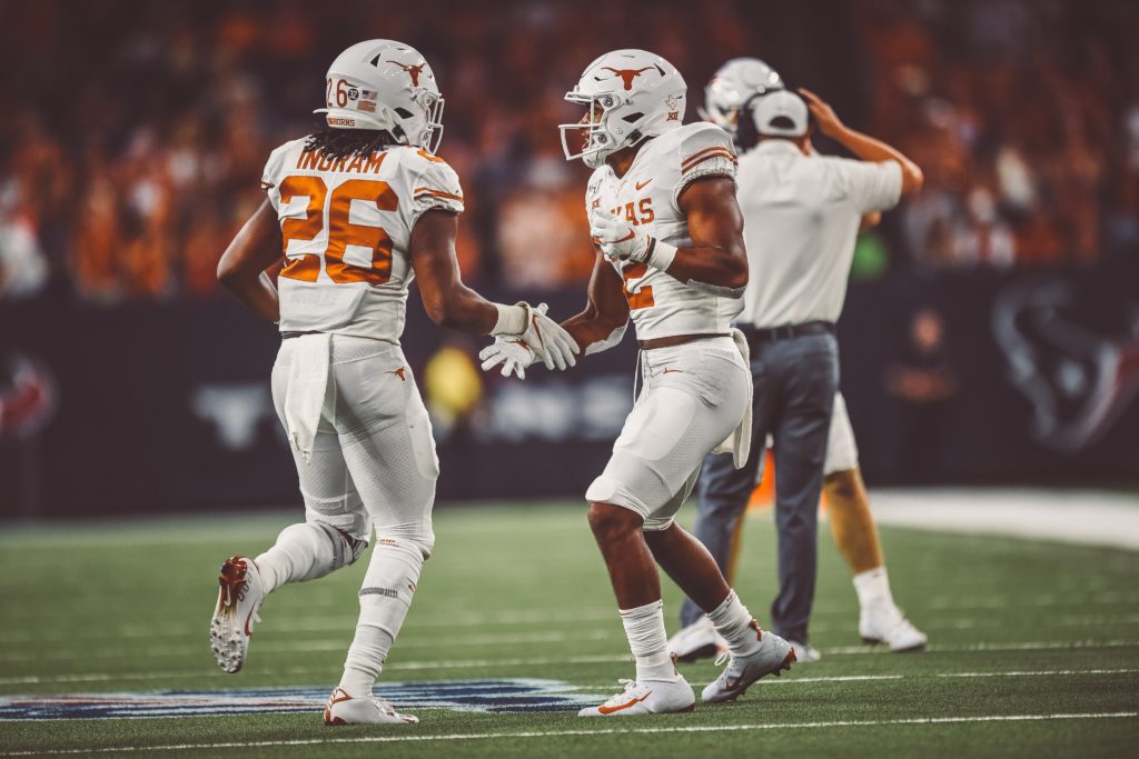 Two UT football players on the field shaking hands