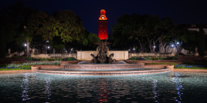 The UT Tower shines with burnt orange lights as seen from Littlefield Fountain