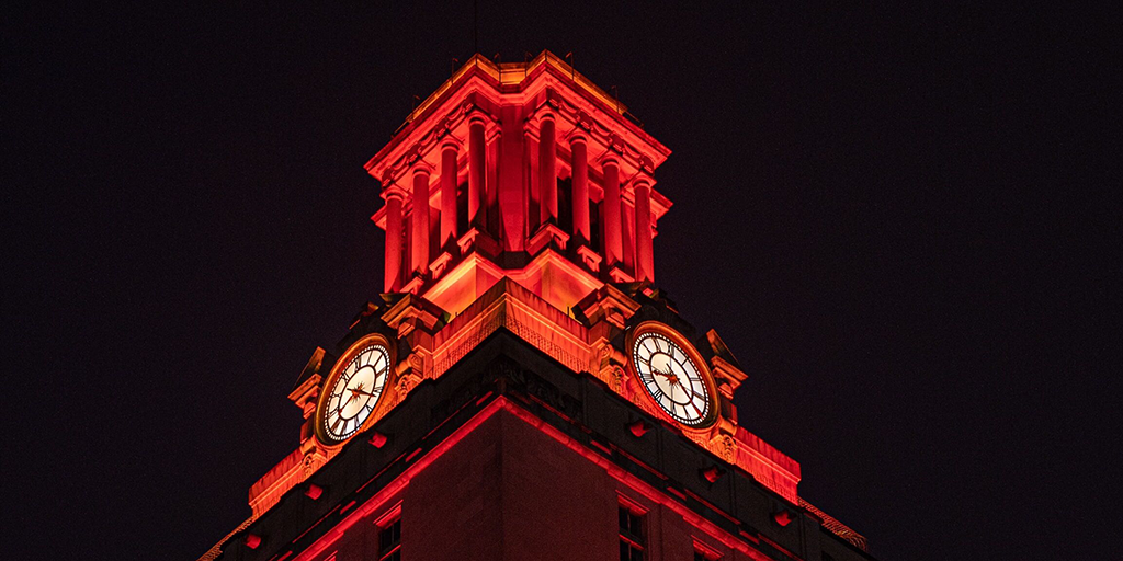 The top of the UT Tower shines with burnt orange lights.