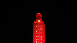 The UT Tower shines with burnt orange lights and the number “22” displayed on its sides.
