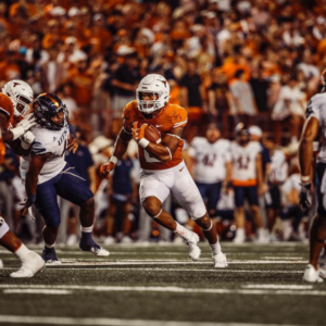 A Texas football player carrying the ball in a game versus UTSA
