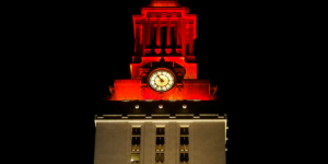 Top of the UT Tower lit in orange with a white base