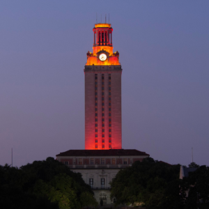 The U.T. Tower shines with burnt orange lights at night.