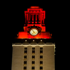 The top of the U.T. Tower shines with burnt orange lights.
