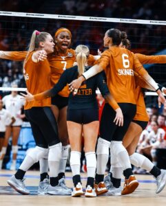 Texas Volleyball players huddle on the court during a game.